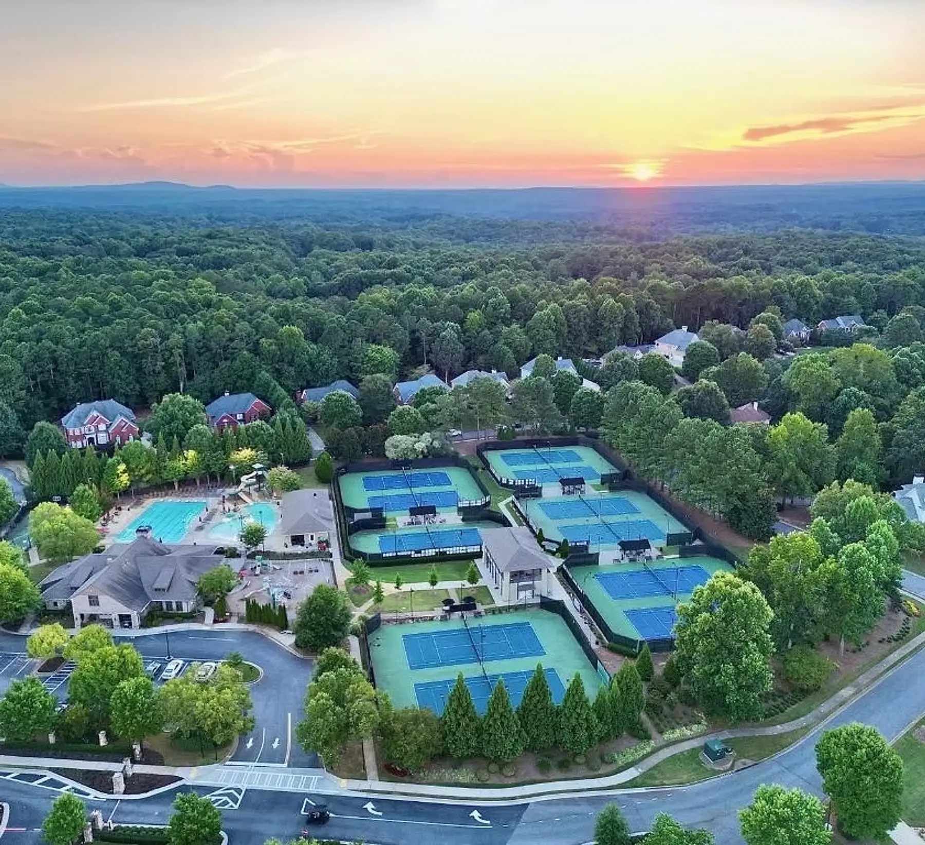 Aerial view of the Crooked Creek courts and clubhouse at sunset in Milton, Georgia