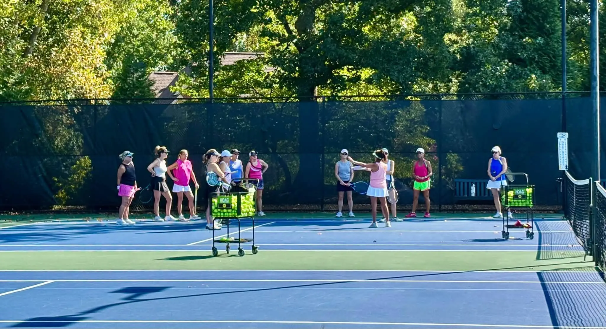 A coach addressing an adult drill group on a sunny court at Crooked Creek